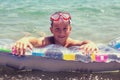 Young boy holding pool mattress in sea