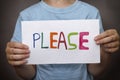 Young boy holds paper note with word Please Royalty Free Stock Photo