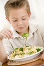 Young boy indoors eating pasta with brocolli Royalty Free Stock Photo