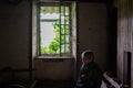 A young boy inside a room in an old crumbling house with an open window. The concept of poverty, homelessness