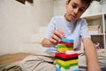 Young boy intently stacking colorful blocks in a cozy home setting