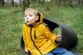A young boy in a jacket lies in a green forest in autumn, spring. Rest, relaxation in nature