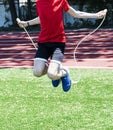 Young boy jumping rope in sunshine aggressively on turf field