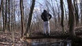 Young boy jumps on smooth narrow log across river. Stability test in nature. Practicing gymnastic elements on a log. Athletic per