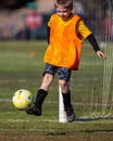 Young boy kicking soccer ball playing goalie in action shot during game Royalty Free Stock Photo