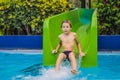 Young boy or kid has fun splashing into pool after going down water slide during summer Royalty Free Stock Photo