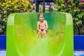 Young boy or kid has fun splashing into pool after going down water slide during summer Royalty Free Stock Photo