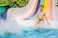 Young boy or kid has fun splashing into pool after going down water slide during summer Royalty Free Stock Photo