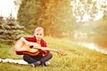 Young boy kid teen child playing guitar in a camp or summer picnic near by river or pond Royalty Free Stock Photo