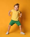 Young boy kid in yellow t-shirt and green shorts poses act like an angry giant monster demonstrates power and hisses with rage