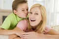 Young boy kissing smiling woman in living room Royalty Free Stock Photo