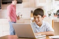 Young boy in kitchen with laptop and paperwork Royalty Free Stock Photo