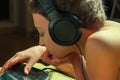 Young boy listening to music or have an e-learning class on his tablet computer attached to a pair of headphones, side