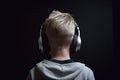 Young boy listening to music with headphones on a black background. Back view, A young boy full rear view with headphone listening Royalty Free Stock Photo