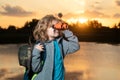 Young boy looking through binoculars. Cute blond kid with binoculars wearing explorer hat and backpack on nature. Child Royalty Free Stock Photo