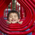 Young boy looking in the hoops of a playground