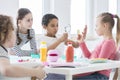 A young boy looking through a magnifying glass and a girl holding a slice of cucumber while other kids are watching during