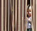 Young boy looking out from behind curtain