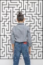 A young boy looks at the maze depicted on the wall and makes a choice or makes a decision. Education concept, growing up