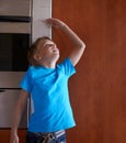 Hes growing fast. A young boy measuring his height at home. Royalty Free Stock Photo