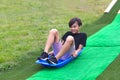 A young boy sledding in summer down a hill