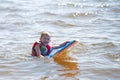 A young boy paddles along in the water on a paddleboard