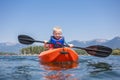 Young Boy paddling a kayak on a beautiful mountain lake