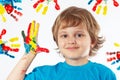 Young boy with painted hands on background of hand prints Royalty Free Stock Photo