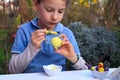 A young boy painting Easter eggs outdoor in France. Easter children creative activity. Royalty Free Stock Photo