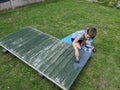 Young boy paints a garden fence panel grey