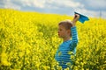 Young Boy with paper Plane against blue sky and Yellow Field Flo Royalty Free Stock Photo