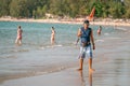 Young boy from parachute beach company posing at seashore line with orange flag used to mark safe area for shore landing. PHUKET