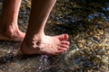 Young child playing barefoot in crystal water at a little creek using his feet and the water spring cooling his feet