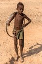 A young boy playing with a bicycle or cart wheel, Epupa falls, Namibia