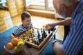 Young boy is playing chess with his grandfather Royalty Free Stock Photo