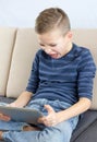 Young boy playing computer game on tablet with angry feeling