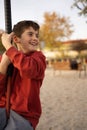 Young boy playing and having fun doing activities outdoors. Happiness and happy childhood concept. Kid swing on rope