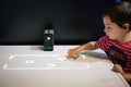 Young boy plays a game projected by XPERIA TOUCH portable smart projector to the desk of table