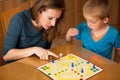 young boy plays ludo game with his mother on a table in livingroom