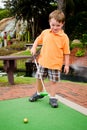 Young boy plays mini golf