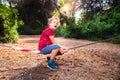 Young boy plays swinging on a barrier of prohibited passage in a forest, concept of challenge of limits