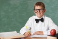 Young boy, portrait and writing at school for learning, education or knowledge with green chalk board. Face of male Royalty Free Stock Photo