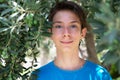 Young boy posing in summer grove among olive trees. Cute smiling happy teen boy 13 years old, looking at camera. Kid`s outdoor Royalty Free Stock Photo