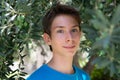 Young boy posing in summer grove among olive trees. Cute smiling happy teen boy 13 years old, looking at camera. Kid`s outdoor Royalty Free Stock Photo