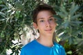 Young boy posing in summer grove among olive trees. Cute smiling happy teen boy 13 years old, looking at camera. Kid`s outdoor Royalty Free Stock Photo