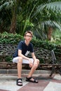 Young boy posing in summer park with palm trees. Cute spectacled smiling happy teen boy 13 years old, looking at camera. Royalty Free Stock Photo