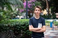 Young boy posing in summer park with palm trees. Cute spectacled smiling happy teen boy 13 years old, looking at camera. Royalty Free Stock Photo