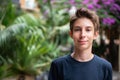 Young boy posing in summer park with palm trees. Cute spectacled smiling happy teen boy 13 years old, looking at camera. Royalty Free Stock Photo