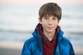 Young boy posing at the winter beach. Cute smiling happy 11 years old boy at seaside, looking at camera. Kid`s outdoor portrait Royalty Free Stock Photo