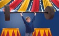 Young boy pretending to be strongman circus performer lifting big barbell